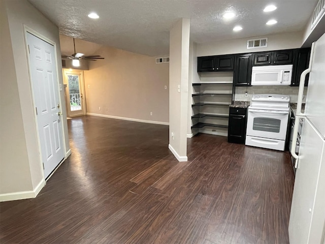 kitchen featuring dark wood finished floors, visible vents, a textured ceiling, dark cabinets, and white appliances