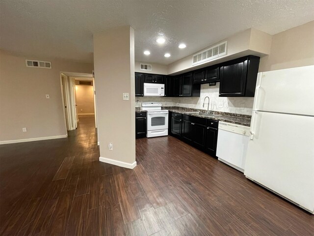 kitchen featuring white appliances, dark cabinetry, a sink, and visible vents