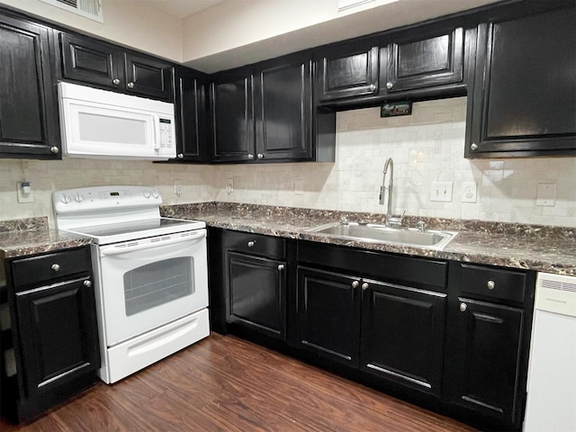 kitchen featuring white appliances, dark wood-type flooring, a sink, and dark cabinetry