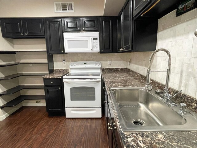 kitchen with white appliances, a sink, visible vents, and dark cabinetry