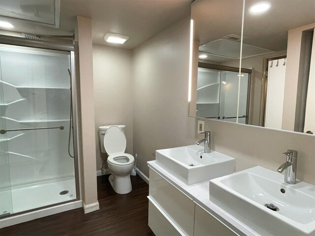 full bath featuring wood finished floors, a stall shower, a sink, and toilet