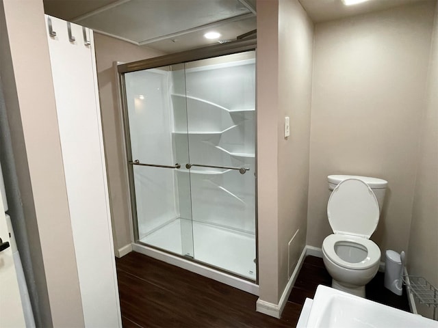 bathroom featuring wood finished floors, a shower stall, toilet, and baseboards