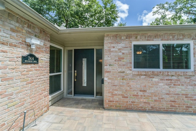 view of exterior entry featuring brick siding