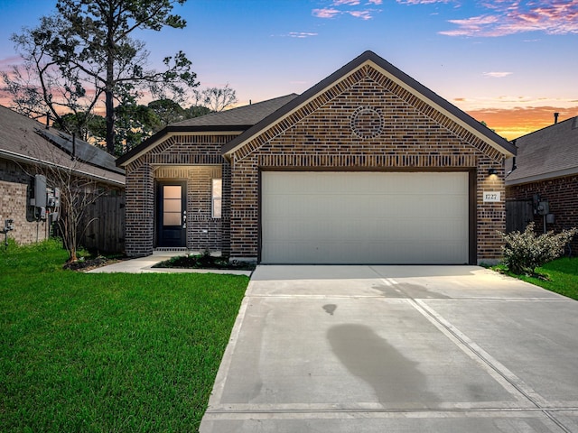 view of front of property featuring brick siding, a lawn, an attached garage, and driveway