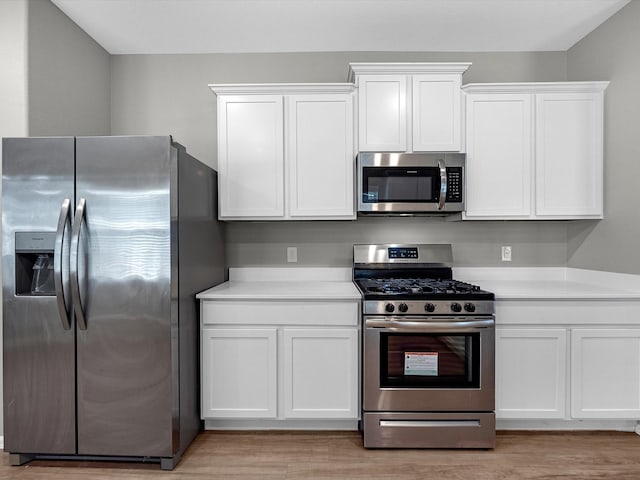 kitchen with light countertops, white cabinets, light wood-type flooring, and stainless steel appliances