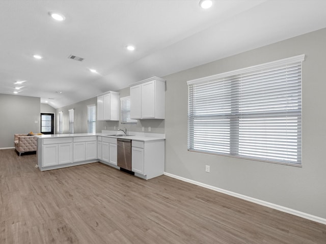 kitchen featuring open floor plan, dishwasher, vaulted ceiling, a peninsula, and white cabinets