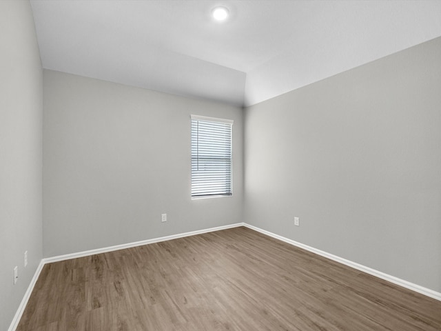 unfurnished room with vaulted ceiling, baseboards, and wood finished floors