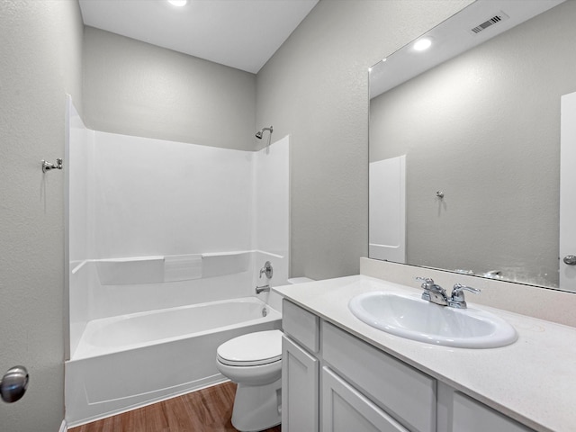 full bath featuring vanity, wood finished floors, visible vents, bathtub / shower combination, and toilet