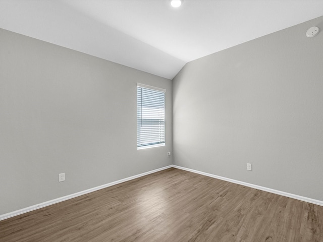 unfurnished room featuring baseboards, lofted ceiling, and wood finished floors