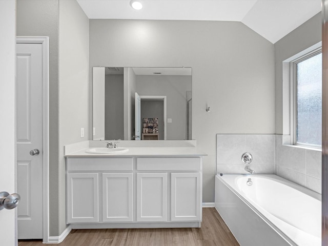 bathroom with a bath, plenty of natural light, vanity, and vaulted ceiling