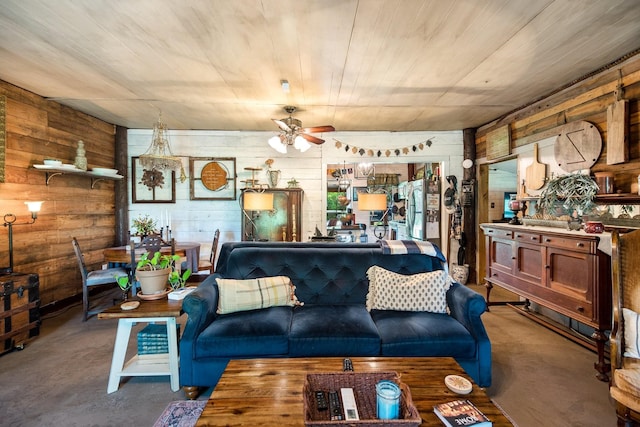 living room with wood walls, ceiling fan, and concrete floors