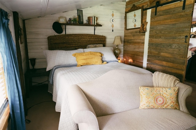 bedroom featuring a barn door, wooden walls, and vaulted ceiling