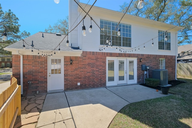 rear view of property featuring brick siding, a patio area, french doors, and fence