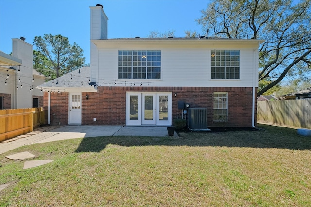 rear view of property featuring central air condition unit, a yard, a fenced backyard, and brick siding