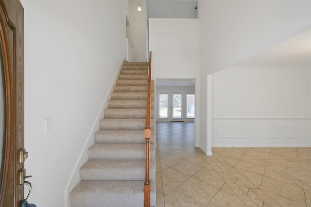 stairway featuring tile patterned floors and a high ceiling