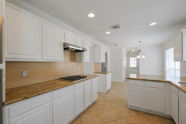 kitchen featuring visible vents, stainless steel gas cooktop, white cabinets, under cabinet range hood, and backsplash