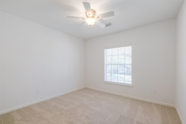 spare room with visible vents, a ceiling fan, baseboards, and light carpet