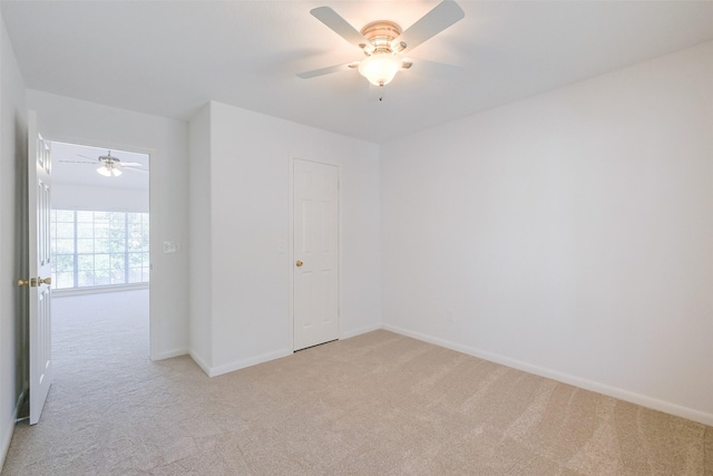 unfurnished bedroom featuring light carpet, a ceiling fan, and baseboards