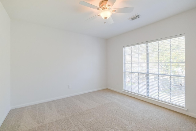 spare room with visible vents, baseboards, light colored carpet, and a ceiling fan