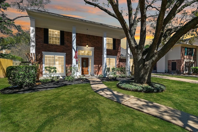 view of front of property with brick siding and a yard