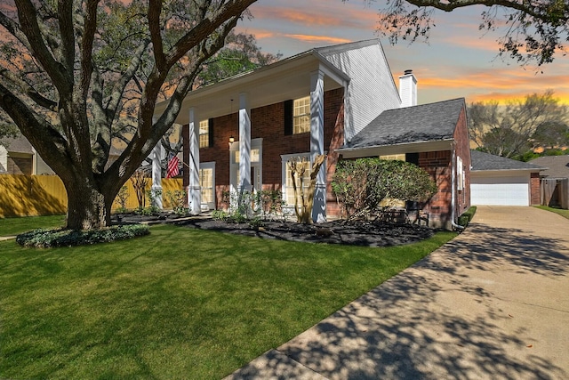 view of front of house with a lawn, fence, covered porch, brick siding, and a chimney