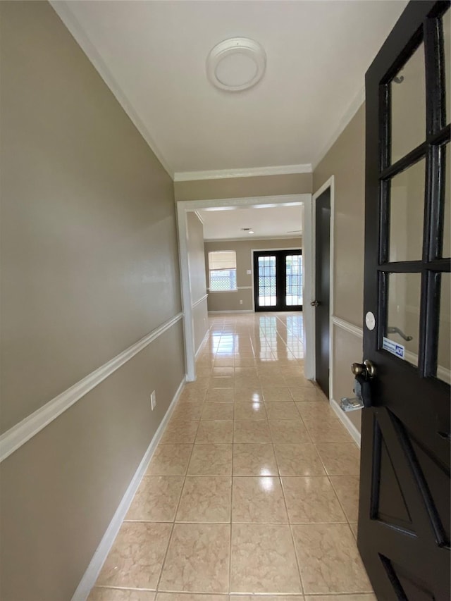 corridor featuring ornamental molding, light tile patterned flooring, and baseboards