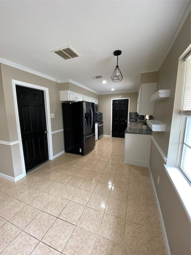 kitchen featuring light tile patterned floors, visible vents, ornamental molding, white cabinets, and black fridge