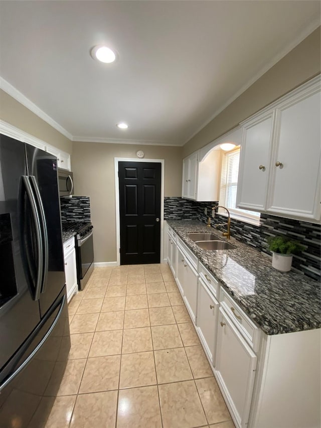 kitchen with stainless steel appliances, light tile patterned flooring, a sink, and white cabinets