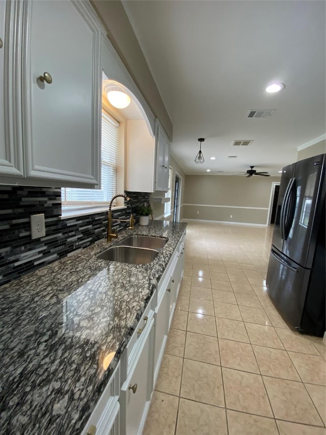 kitchen featuring light tile patterned floors, visible vents, black fridge with ice dispenser, white cabinetry, and a sink