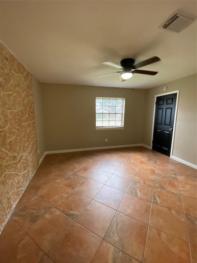 empty room featuring ceiling fan, visible vents, baseboards, and light tile patterned flooring