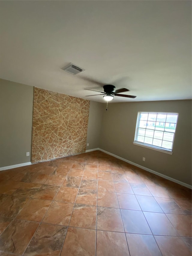 tiled spare room with baseboards, visible vents, and a ceiling fan