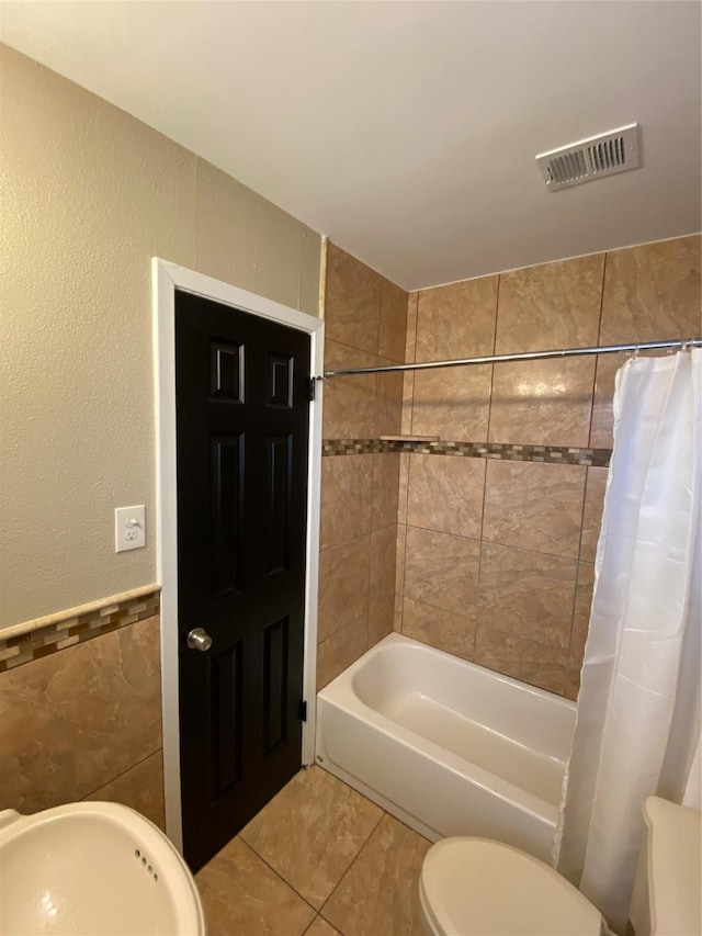 bathroom with toilet, a sink, visible vents, tile patterned floors, and shower / bath combo with shower curtain