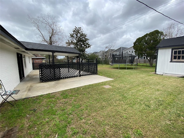 view of yard with a trampoline, a patio area, a fenced backyard, and an outdoor structure