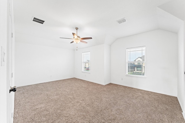 carpeted spare room with lofted ceiling, baseboards, visible vents, and a ceiling fan