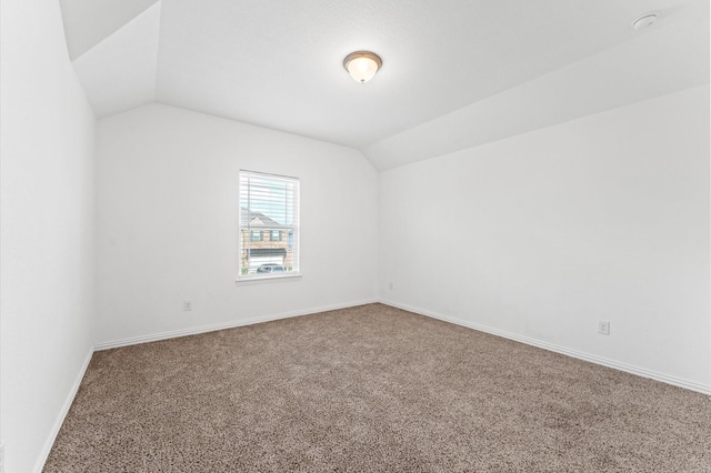 unfurnished room featuring lofted ceiling, carpet, and baseboards