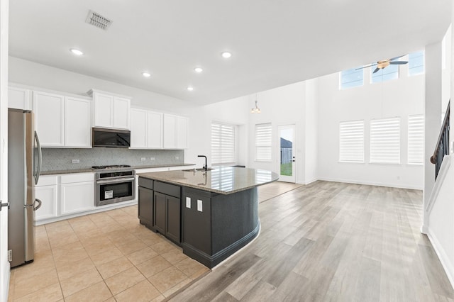 kitchen featuring a sink, visible vents, appliances with stainless steel finishes, light stone countertops, and tasteful backsplash