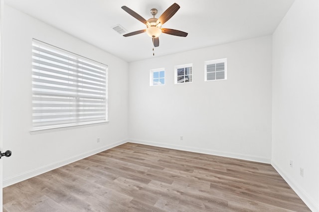 spare room with a ceiling fan, visible vents, baseboards, and wood finished floors