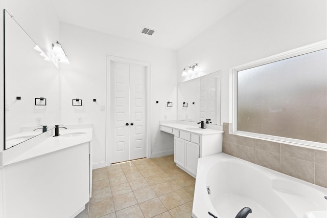 full bathroom featuring a garden tub, visible vents, two vanities, and a sink