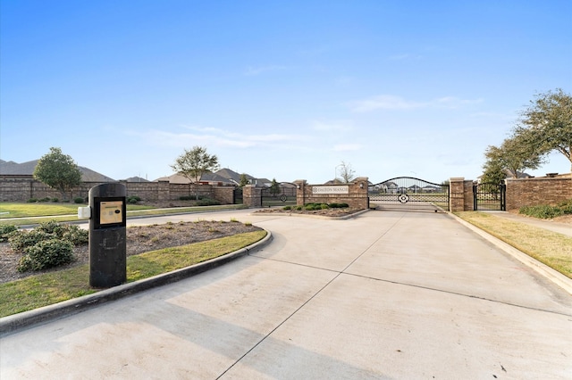 view of street featuring a gate, a gated entry, and curbs