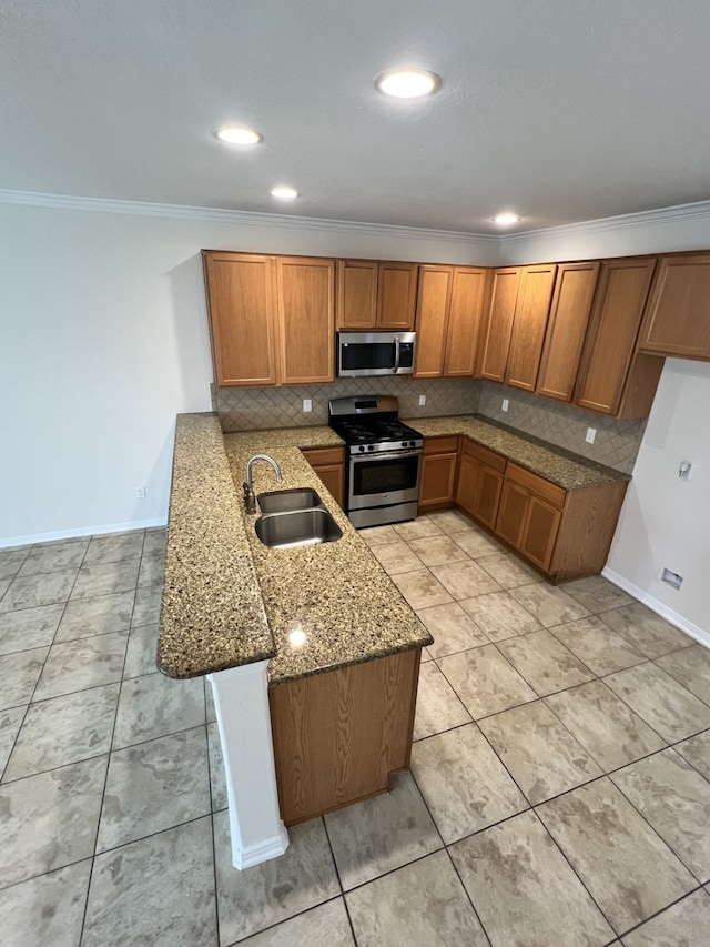 kitchen featuring stone counters, a peninsula, a sink, appliances with stainless steel finishes, and brown cabinetry