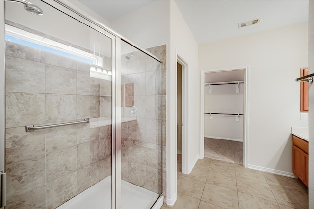 full bath featuring vanity, visible vents, baseboards, a spacious closet, and a stall shower