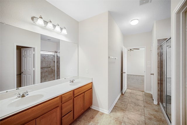 bathroom with double vanity, a shower stall, visible vents, and a sink