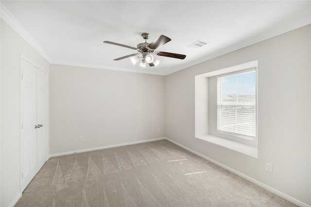 spare room featuring light carpet, baseboards, visible vents, a ceiling fan, and ornamental molding