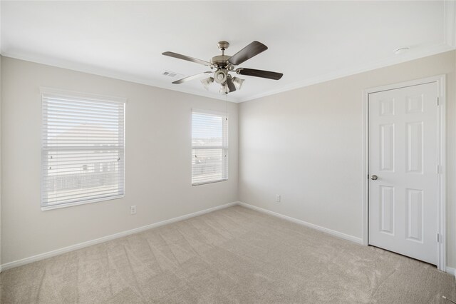 unfurnished room with baseboards, visible vents, light colored carpet, ceiling fan, and ornamental molding