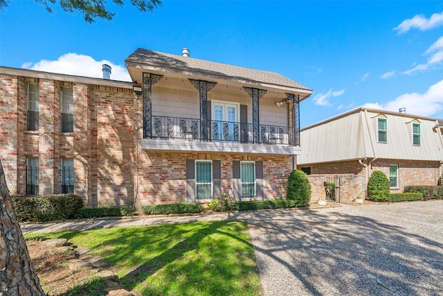 view of front of house featuring brick siding and a balcony