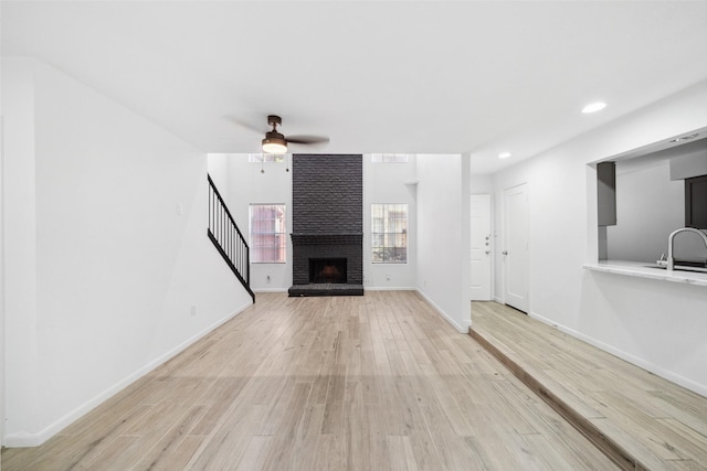 unfurnished living room with baseboards, recessed lighting, a fireplace, wood finished floors, and a ceiling fan