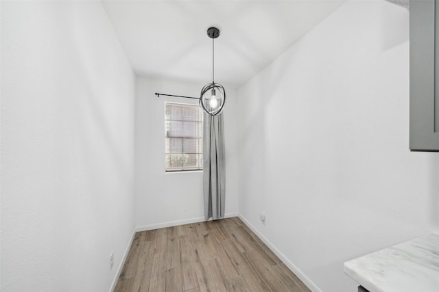 unfurnished dining area featuring baseboards and light wood-style floors