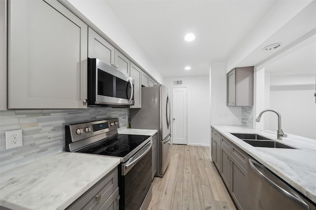 kitchen with a sink, stainless steel appliances, light wood-style flooring, and gray cabinets