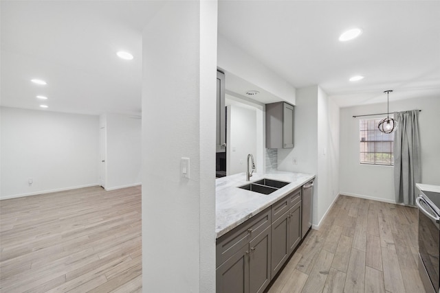 kitchen featuring light wood-type flooring, gray cabinetry, a sink, appliances with stainless steel finishes, and baseboards