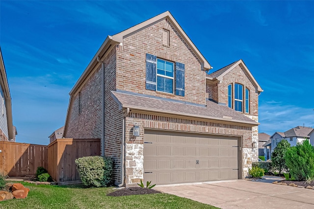 traditional-style home with a garage, concrete driveway, stone siding, fence, and brick siding